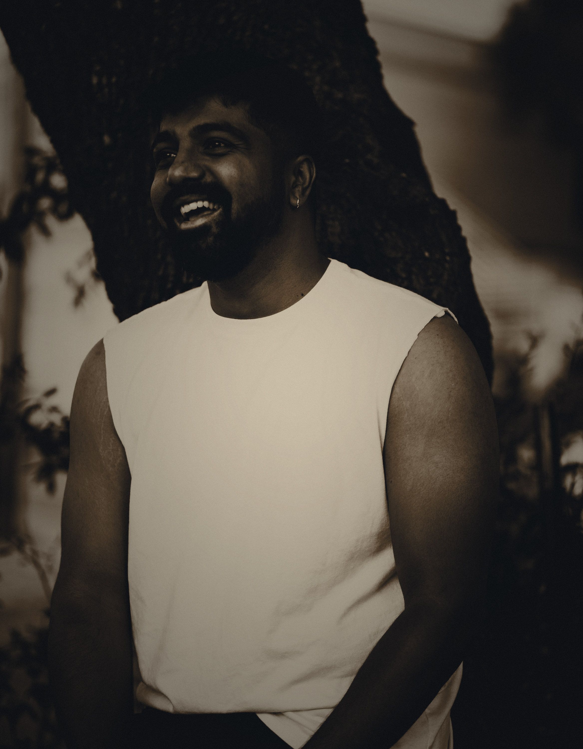 Adi Rao laughing beside the trunk of an oak, at dusk.
